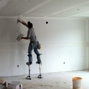 A picture of a man on the plastering stilts